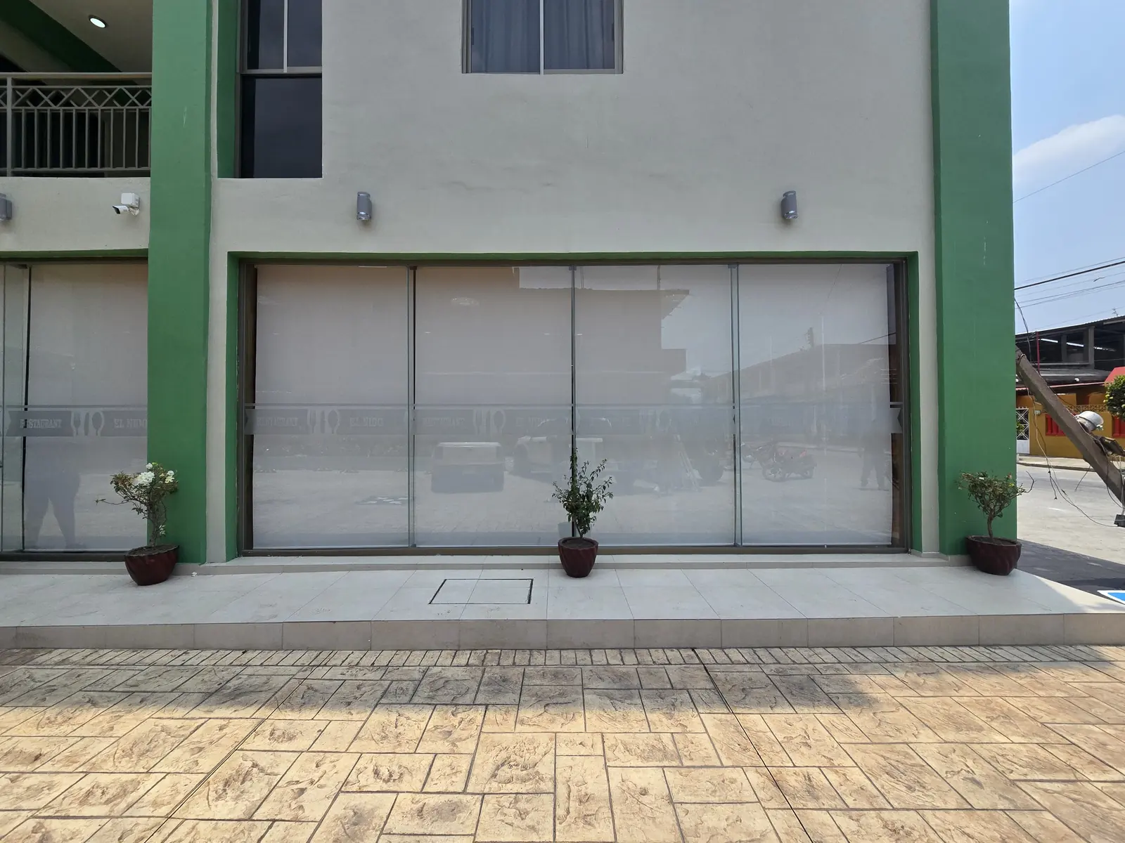 Local comercial con persianas de malla solar en la fachada de cristal
